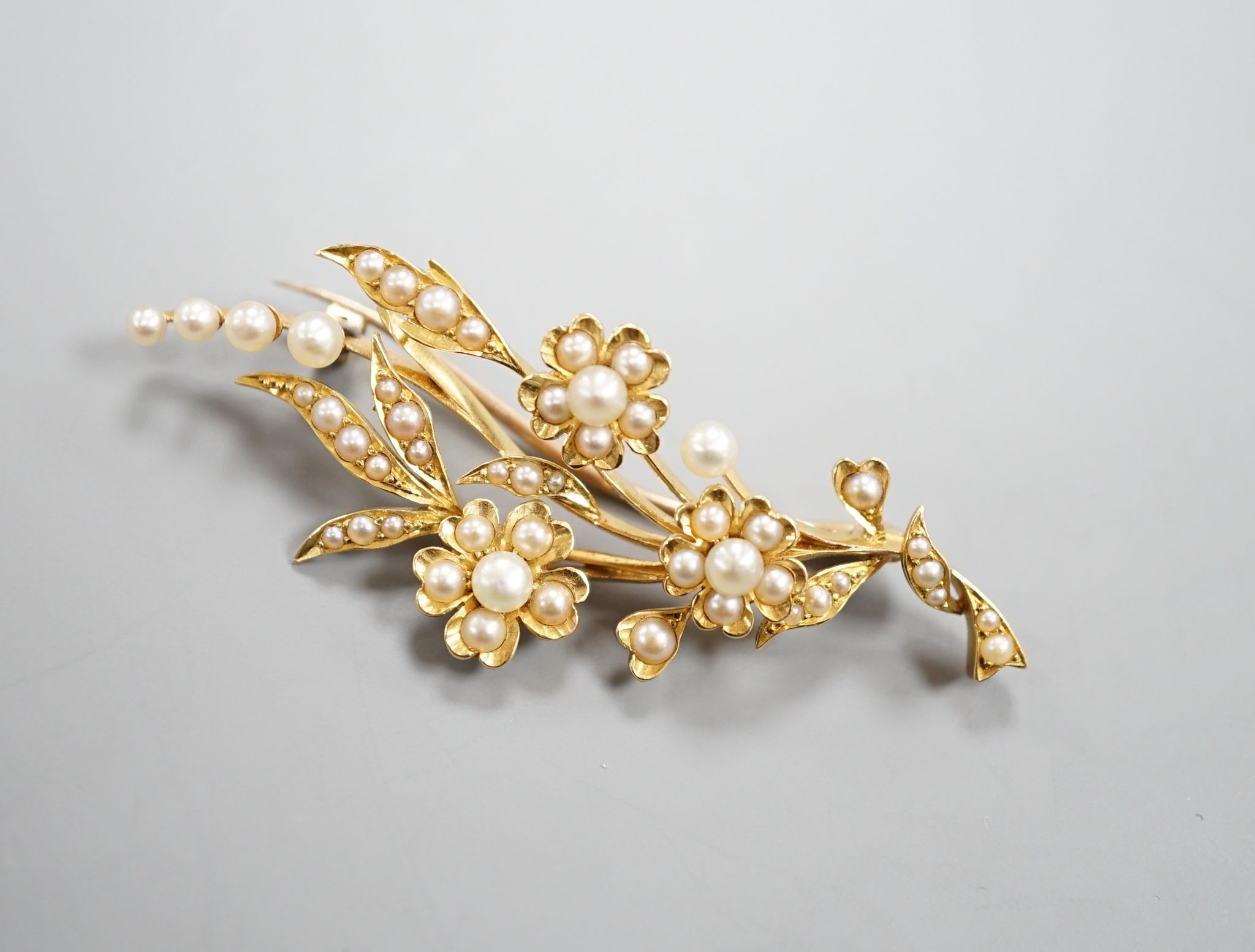 An Edwardian yellow metal and seed pearl set spray brooch, 58mm, gross weight 8.7 grams.